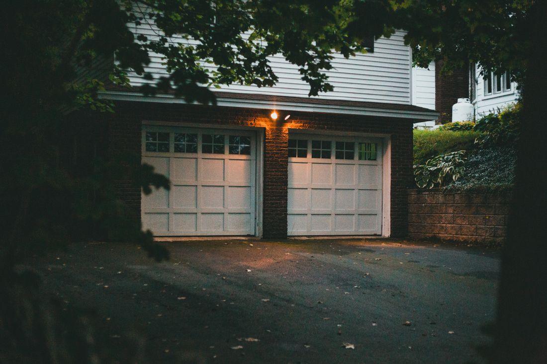 A two-car garage with a dark asphalt driveway in front