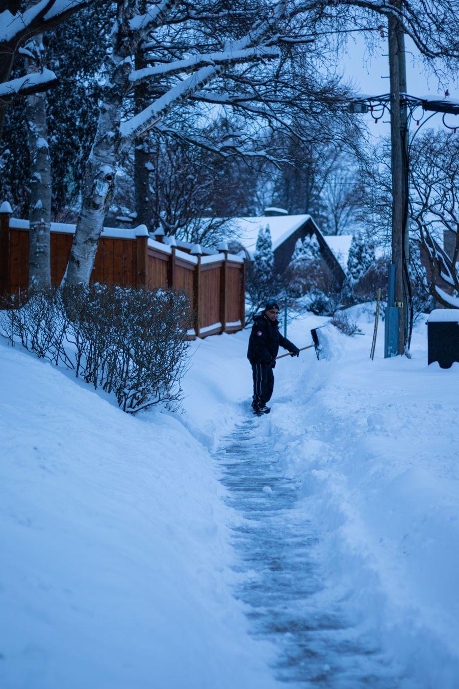 A person shoveling a snowy sidewalk
